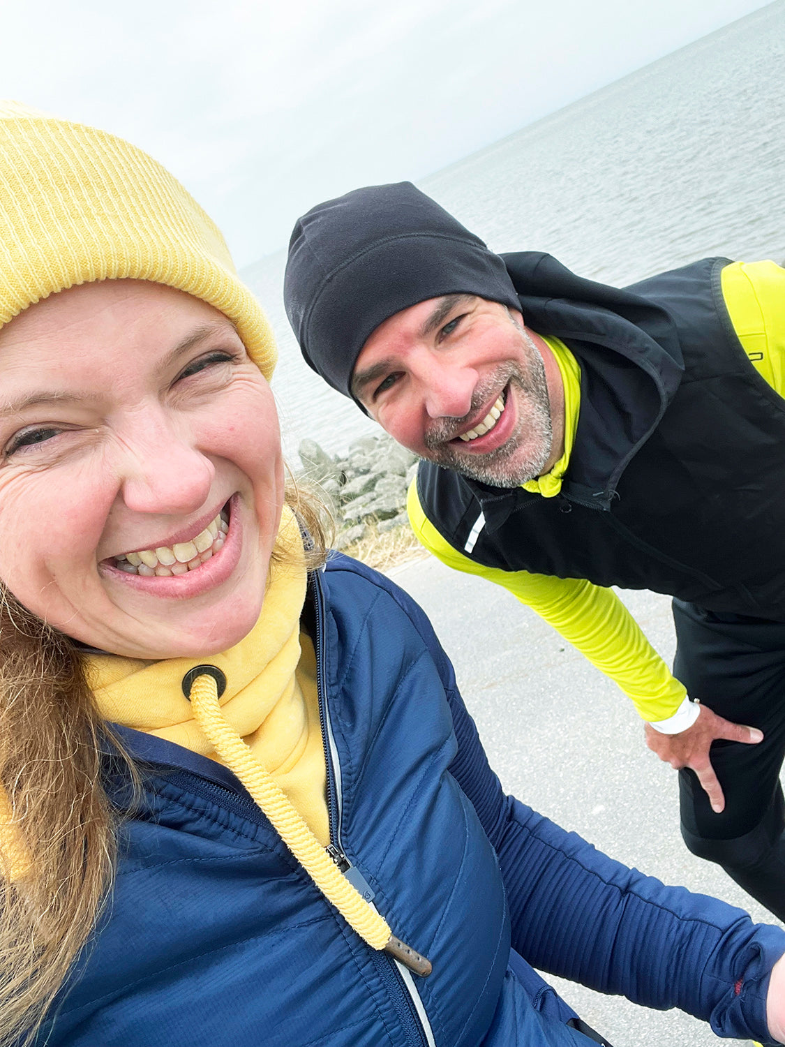 Christiane und Kai-Uwe Kalkhake am Deich. Beide tragen ein Beanie und lachen in die Kamera.